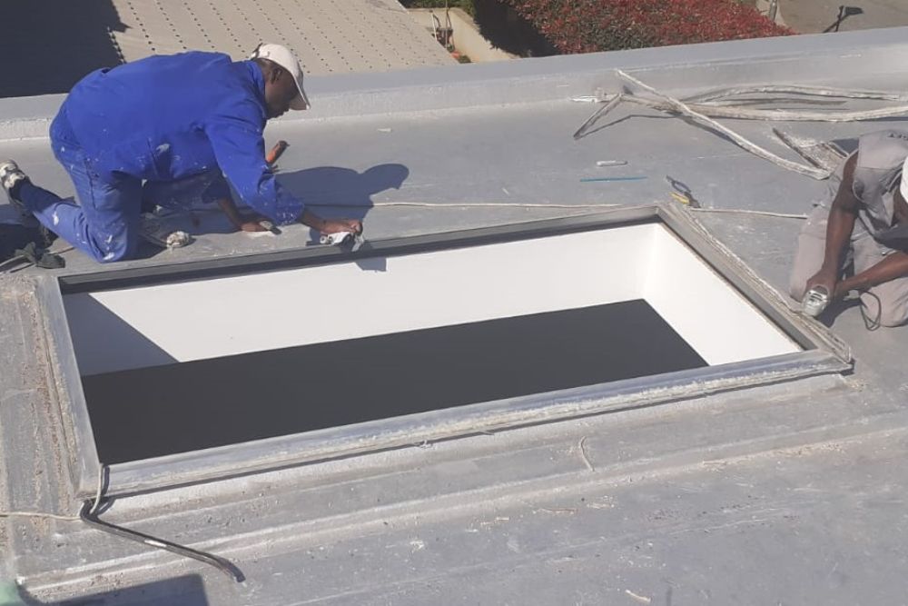 Two men installing a skylight on a roof in Dallas, TX, showcasing professional roofing services.