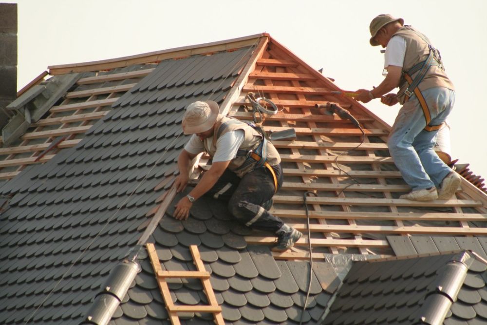 Two men performing roof maintenance on a wooden frame in Dallas, TX, ensuring structural integrity and safety.