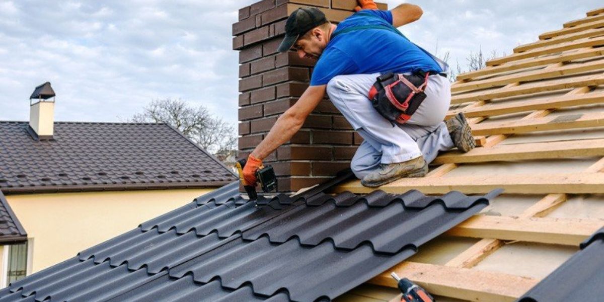 A worker applies metal roofing on a rooftop, illustrating the benefits of reroofing services over complete roof replacement.