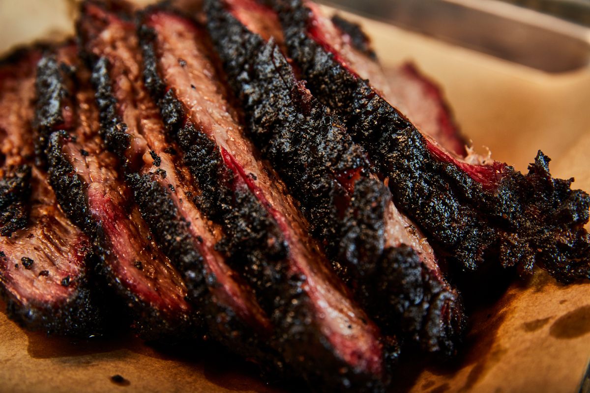  A close-up view of a succulent piece of meat resting on a white paper plate, showcasing its texture and color.