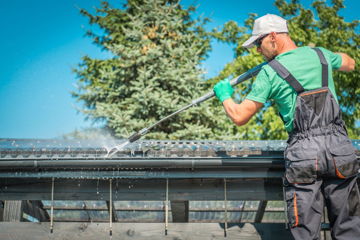 A man in overalls and work gloves cleans a roof, promoting the message "Keep Your Roof Clean."