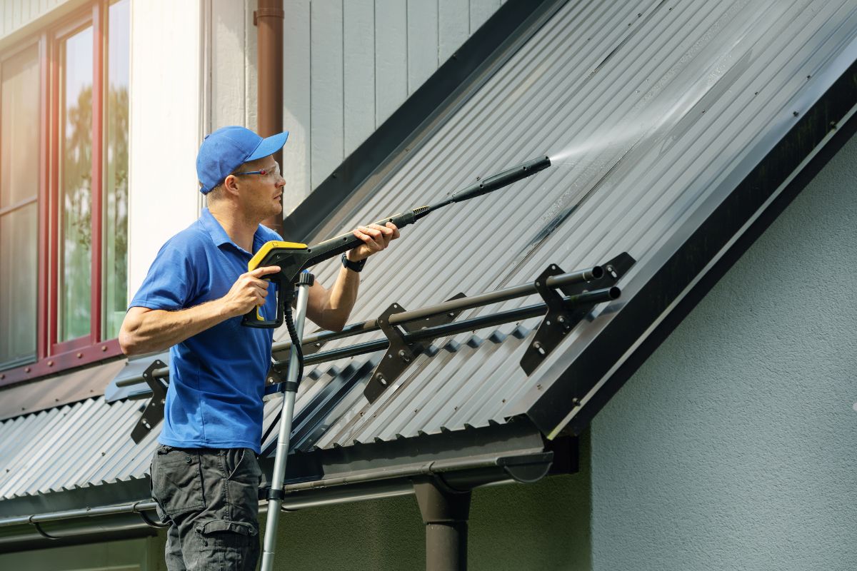 A man in a blue shirt and hat cleans a roof, emphasizing the importance of maintaining a clean roof.
