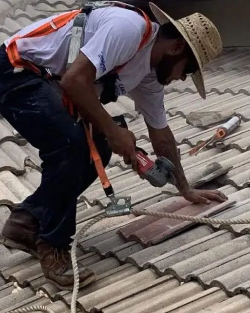 A man repairs a tile roof with a hammer, showcasing skilled roofing service in Dallas, TX.